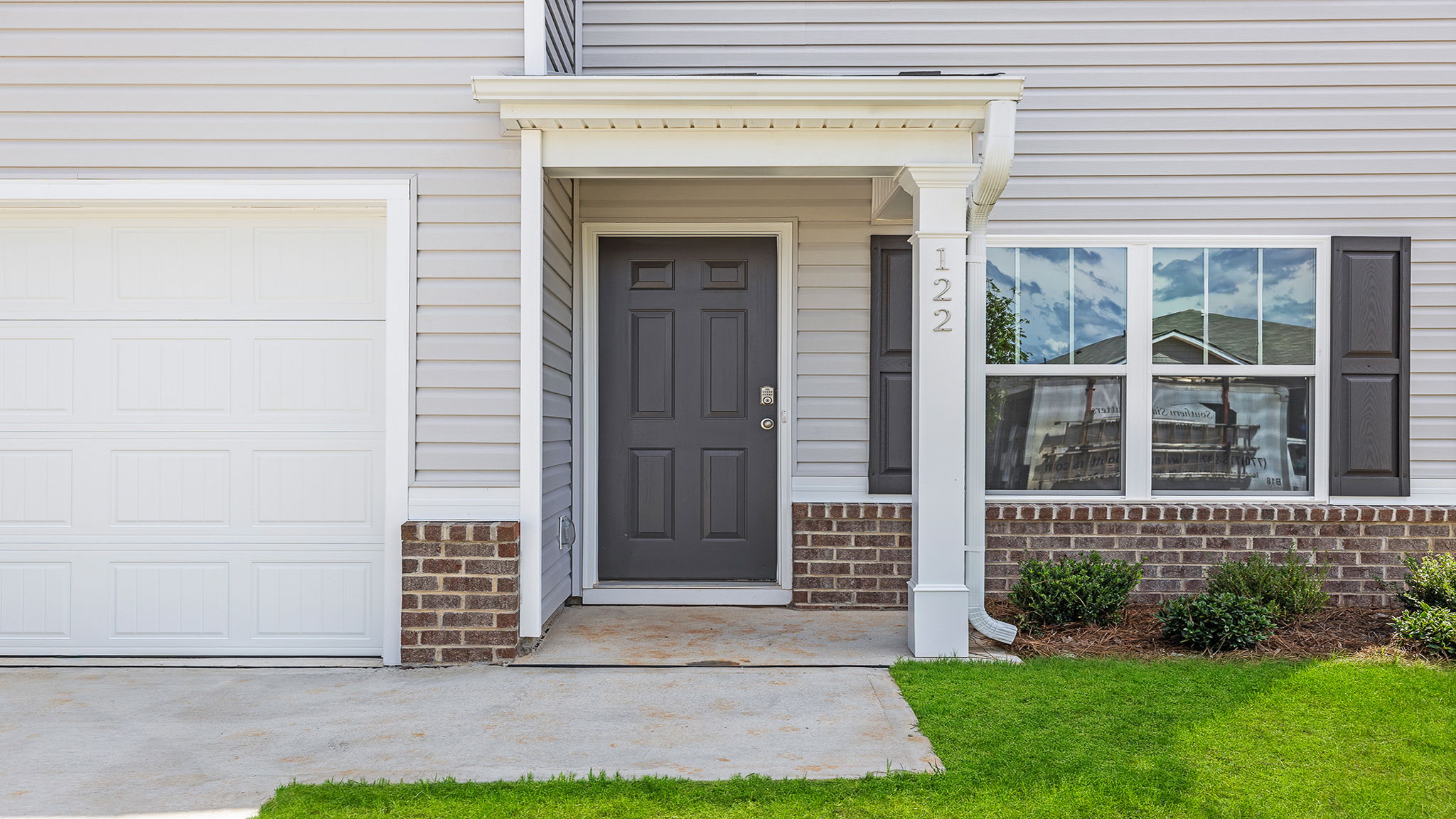 View of the front of Belhaven home with driveway and covered front porch entry.