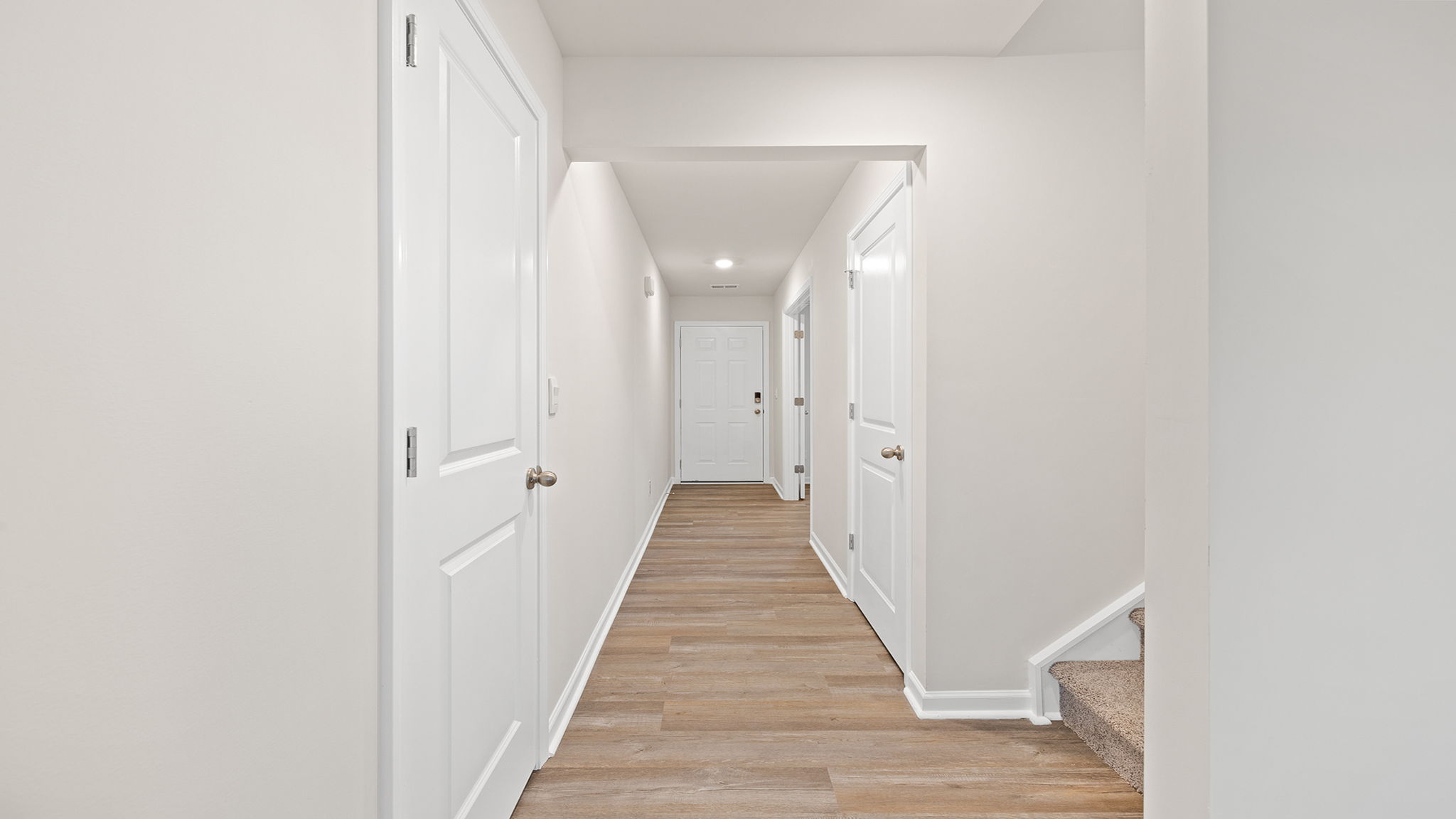 View of hallway toward the entrance and peek at stairwell.