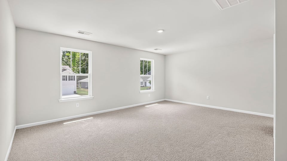 Primary bedroom with carpet and windows.
