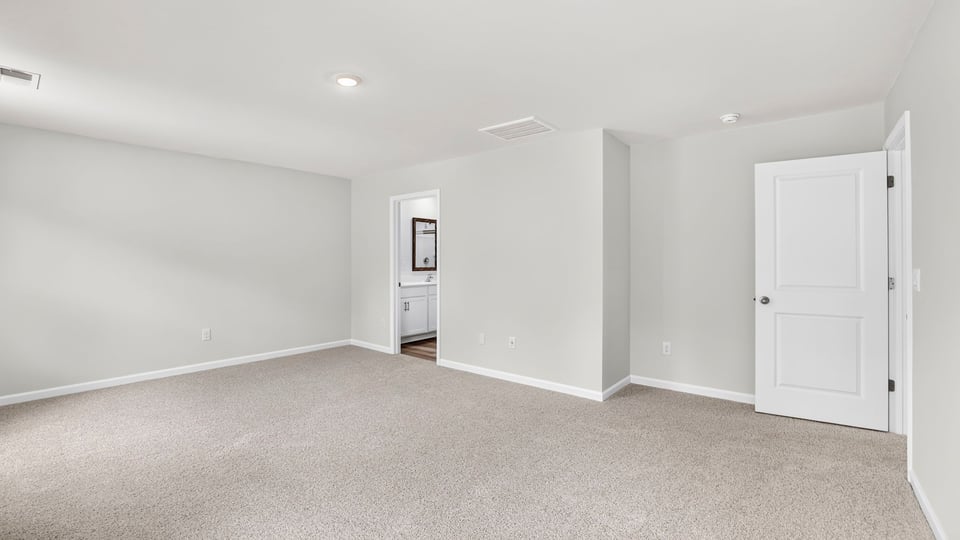 Primary bedroom with carpet and windows.