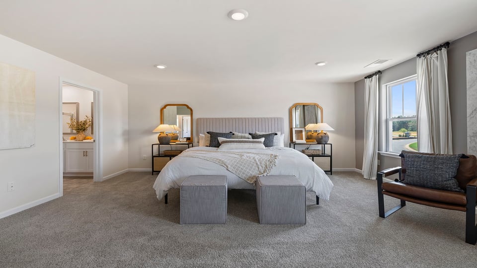 Primary bedroom with carpet and windows.