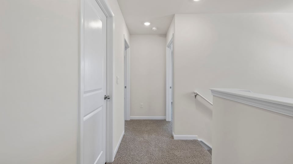 Hallway to bedrooms with carpet.