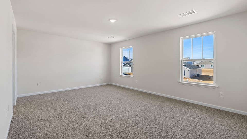 Primary bedroom with carpet and windows.