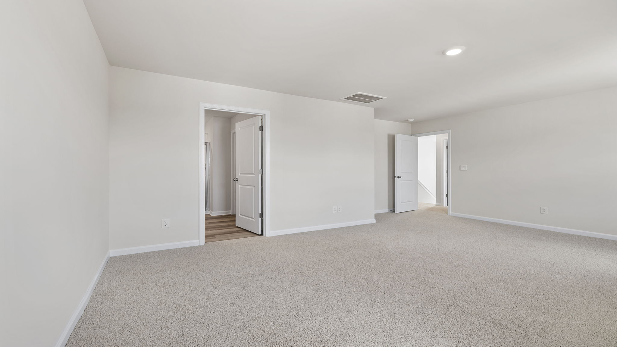 Primary bedroom with windows and carpet.