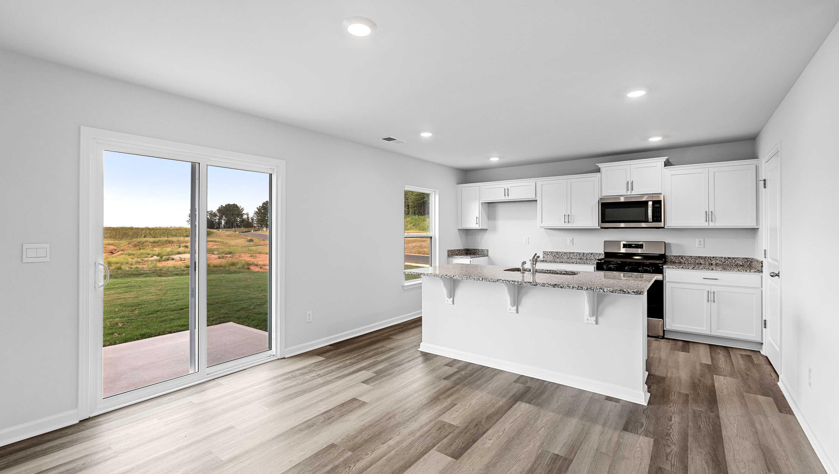 View of open kitchen with island and door to the back yard.