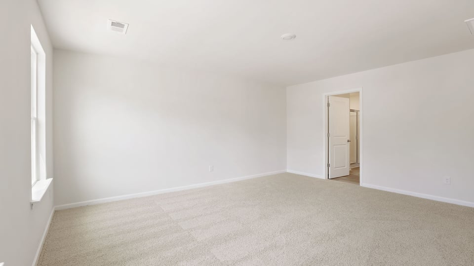 Primary bedroom with carpet and window.