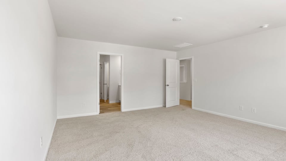 Primary bedroom with carpet and window.