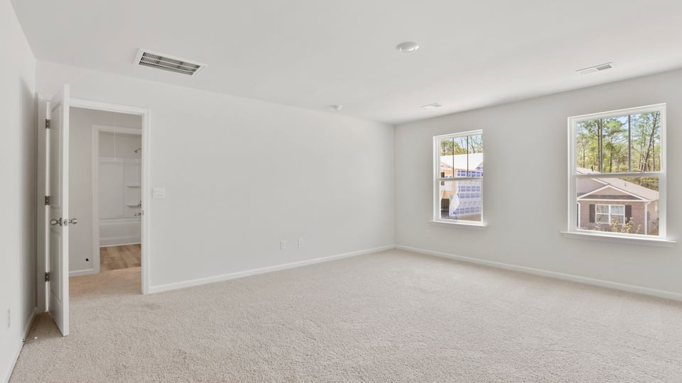 Primary bedroom with carpet and window.
