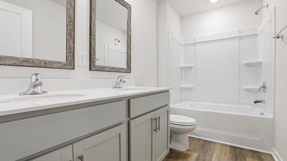 Hall bathroom with dual sink vanity and combination shower / tub.