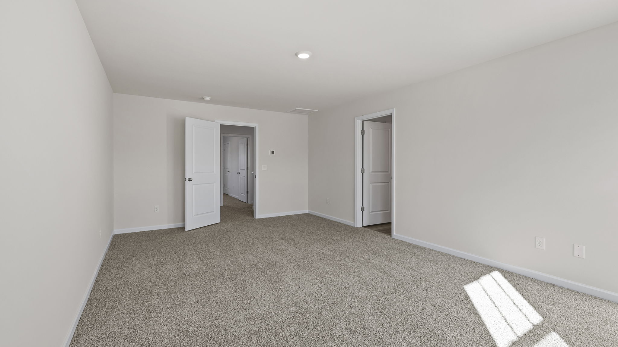 Primary bedroom with windows and carpet.
