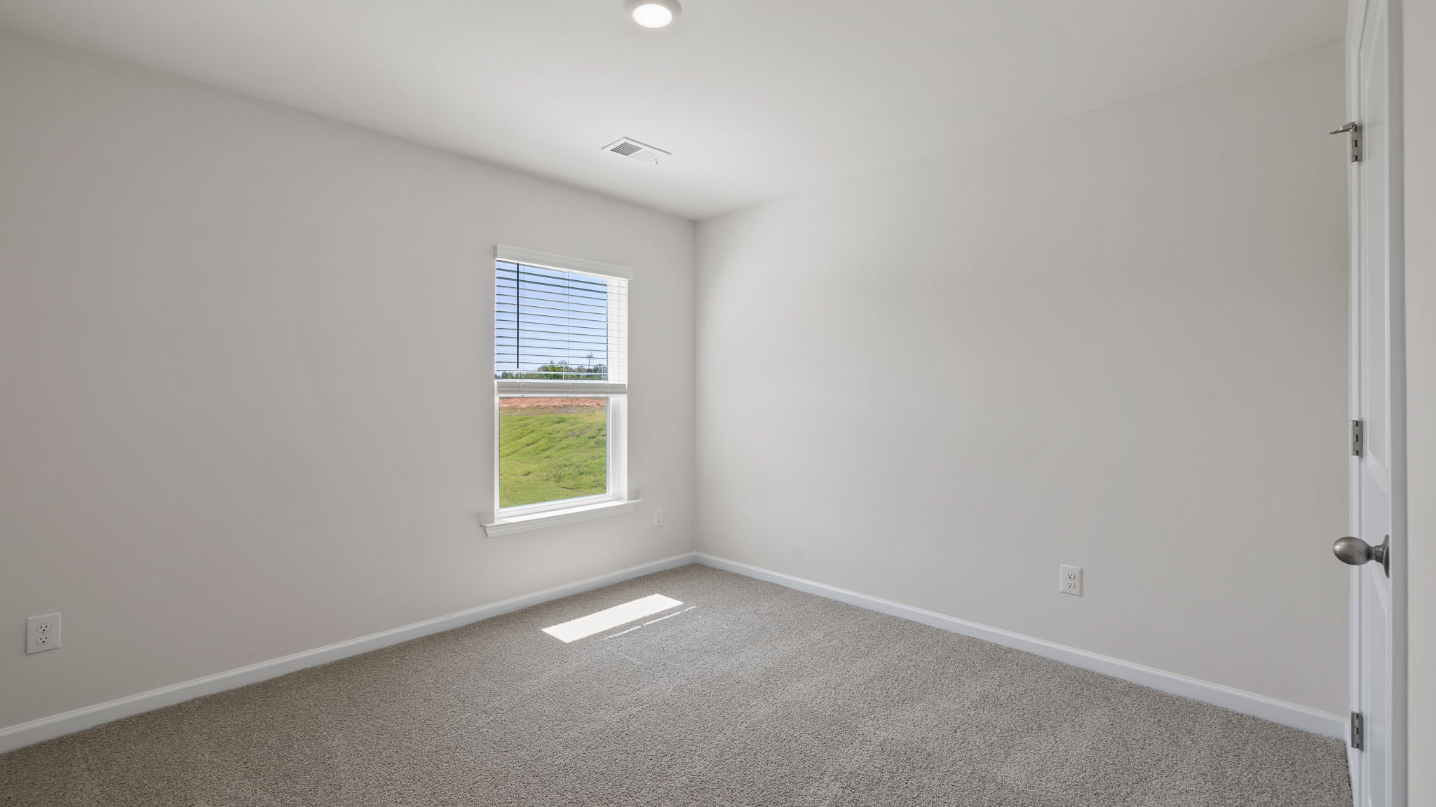 Bedroom on the main level with window and carpet.