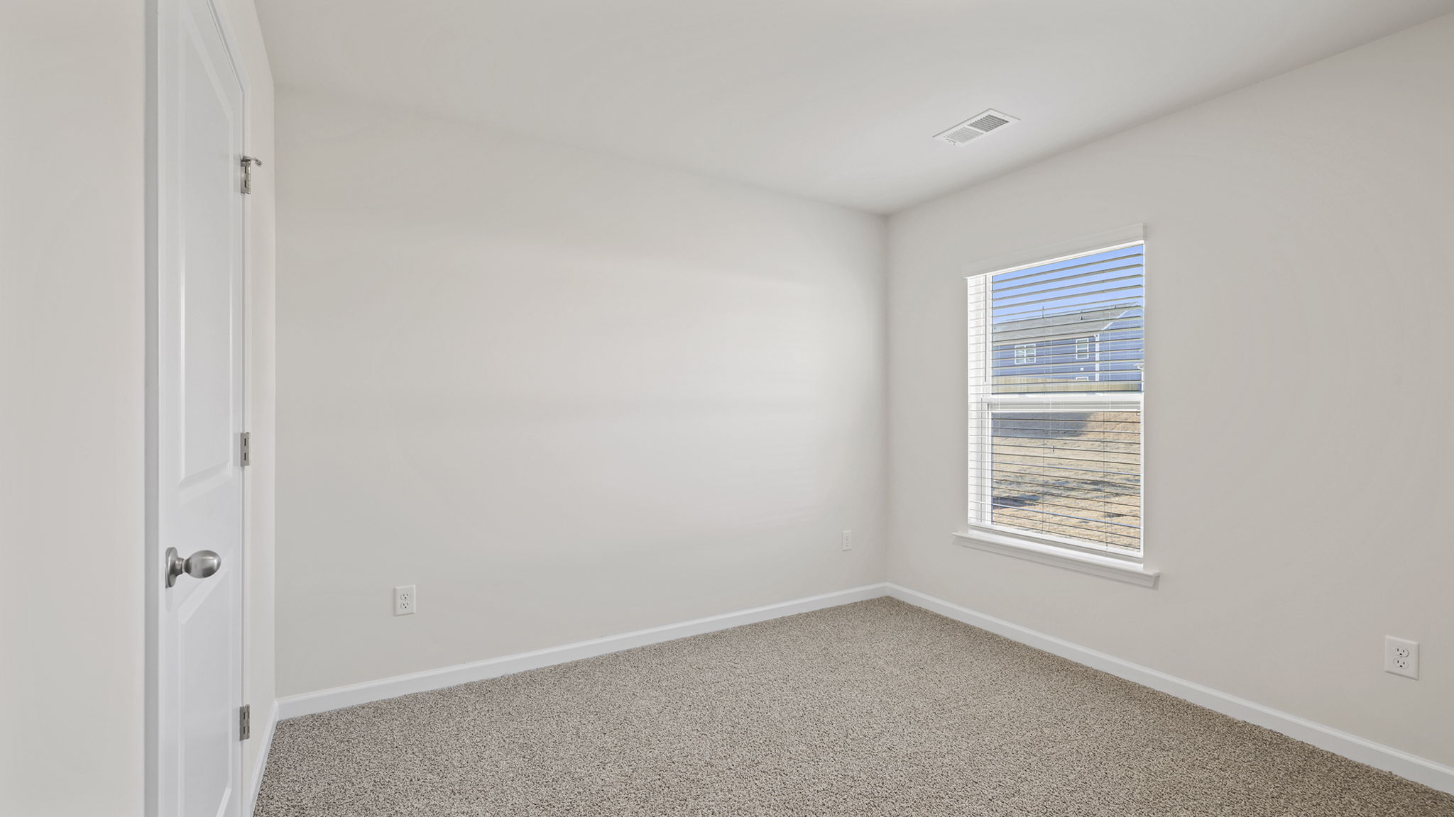 Bedroom on main level with window and carpet.