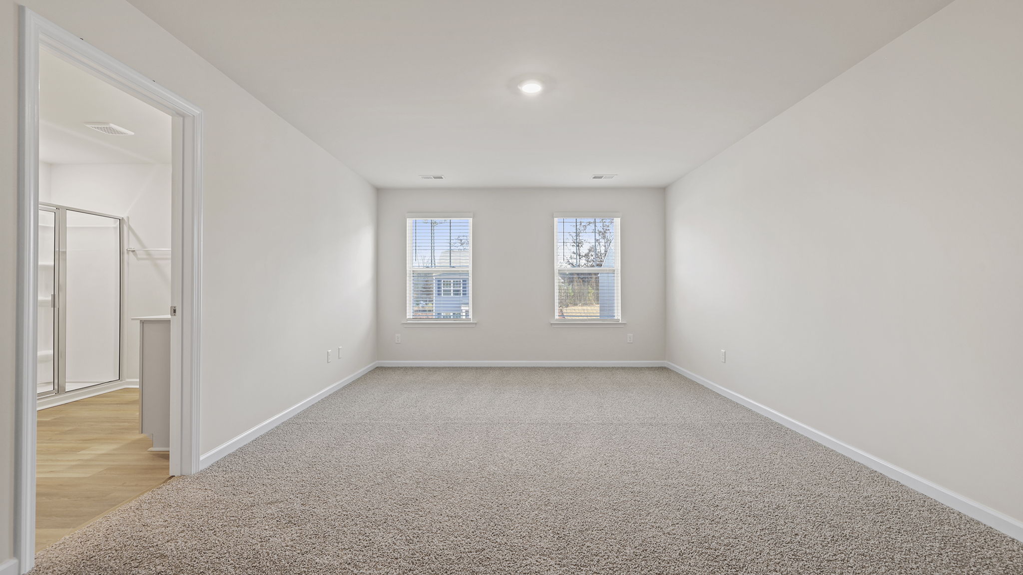 Primary bedroom with windows and carpet.