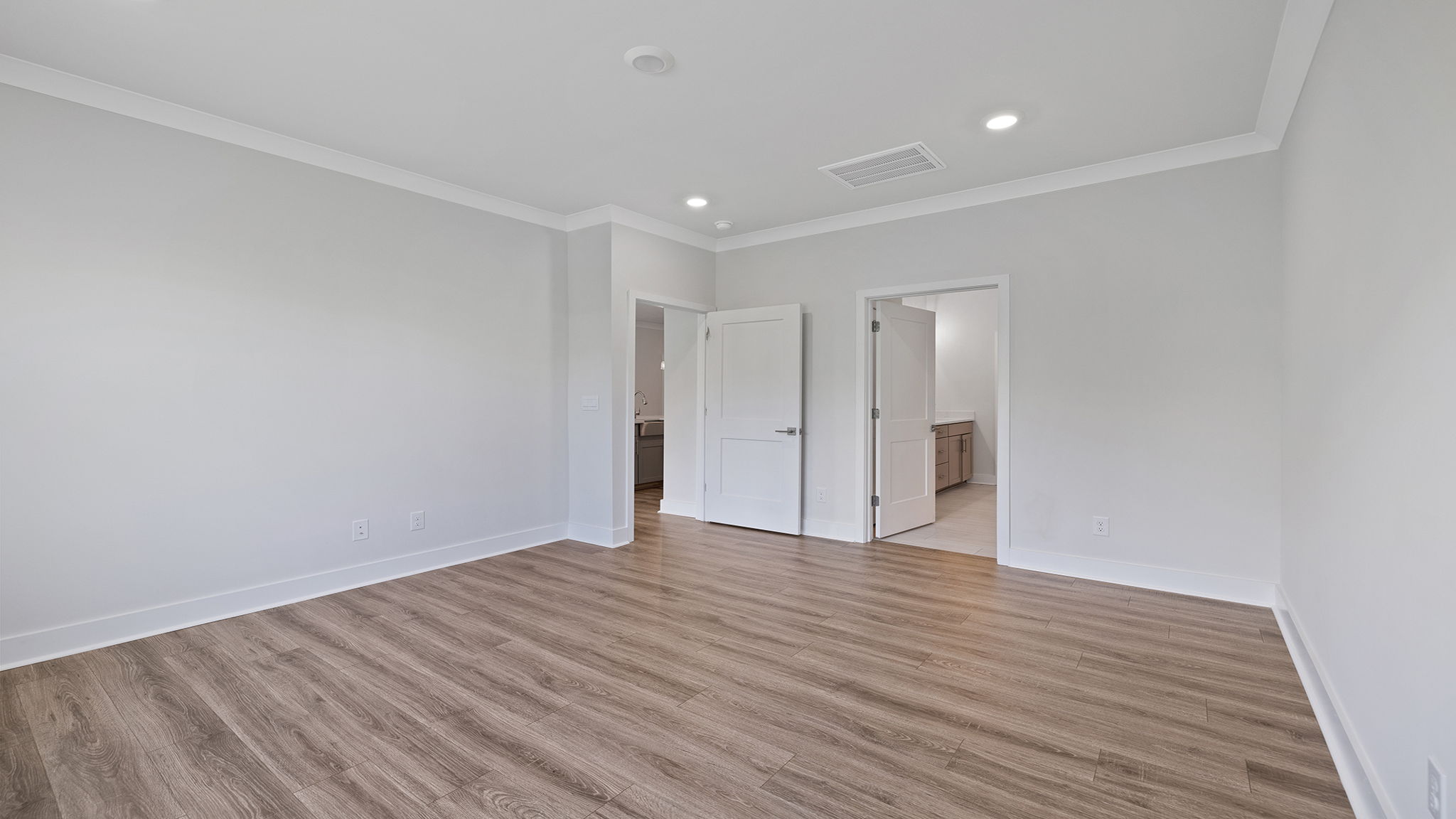 Primary bedroom on the main level with large window and recessed lighting.