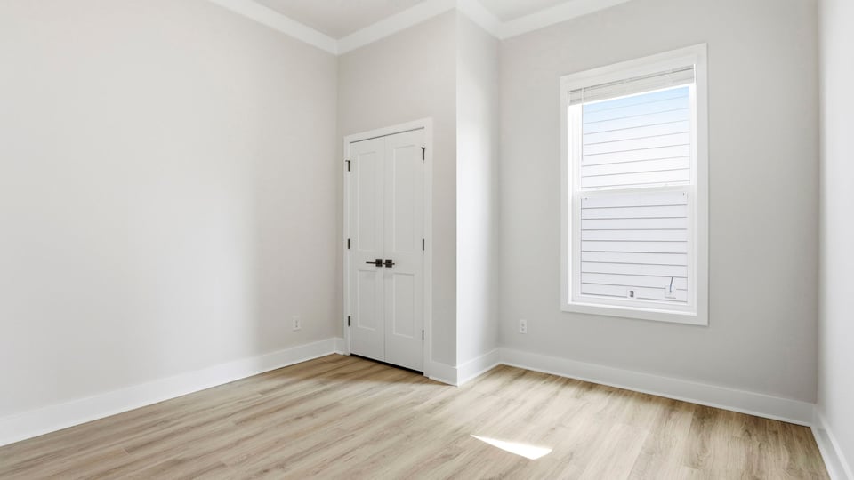 Bedroom with window and laminate flooring.