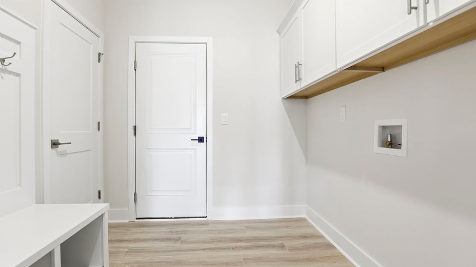 Walk-in laundry room with cabinets and drop zone.