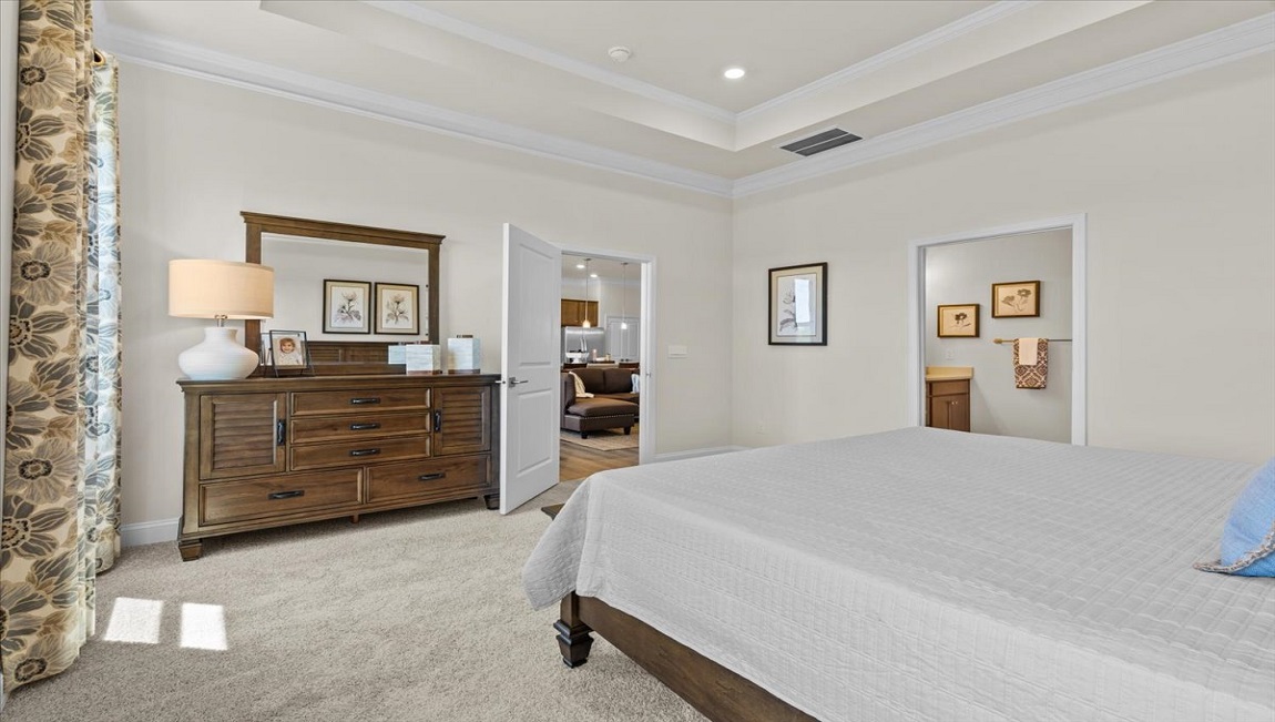 Primary bedroom with carpet and windows.
