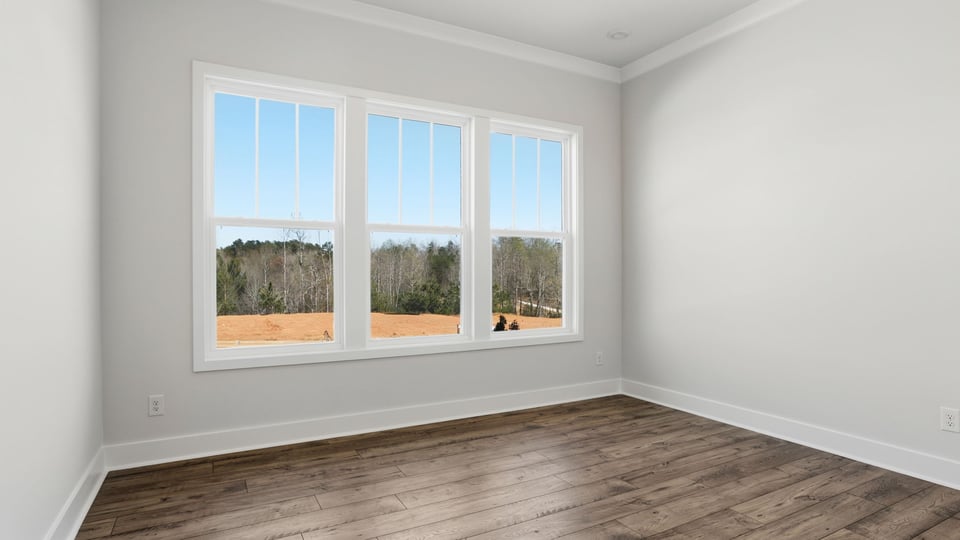 Bedroom with large windows and laminate flooring.