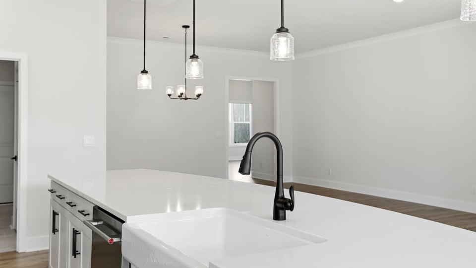 Kitchen island hosts the sink and dishwasher with a view of the breakfast area and family room.