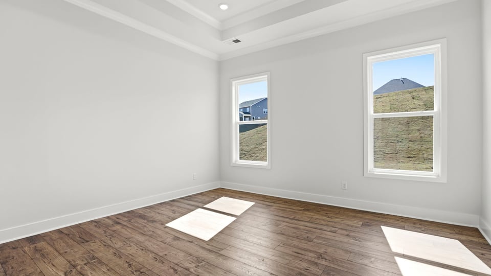 Primary bedroom on the main level with trey ceiling, recessed lighting and two windows