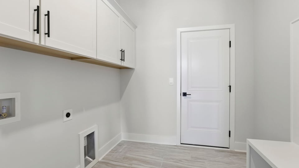 Walk-in laundry room with cabinets and drop zone.