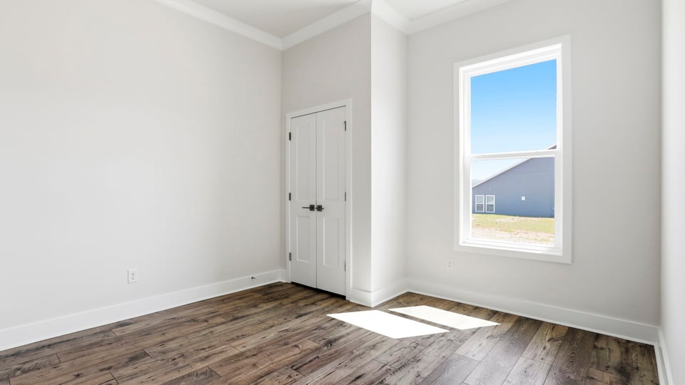 Bedroom with window and laminate flooring.