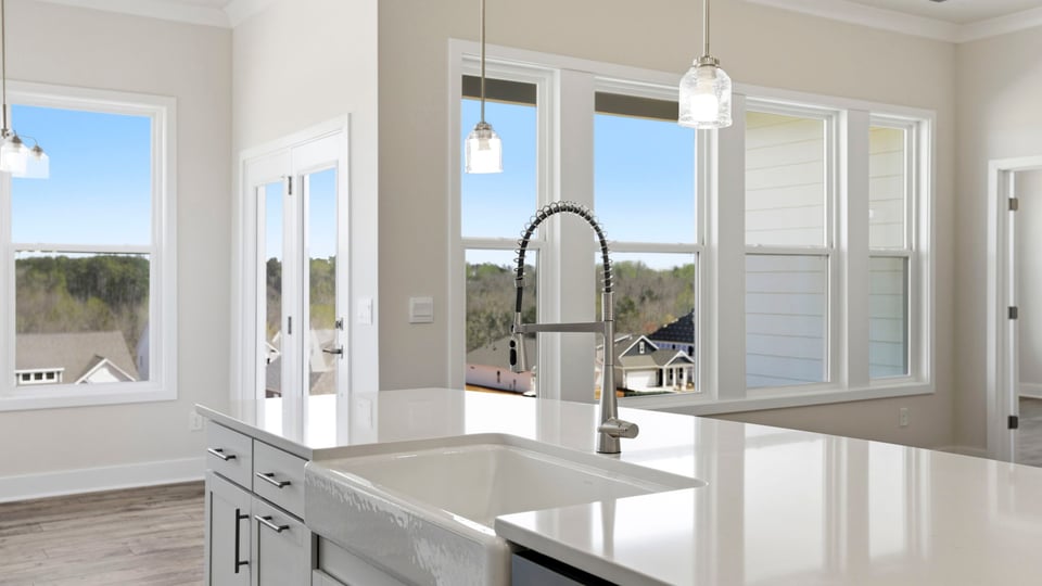 Kitchen island hosts the sink and dishwasher with a view of the breakfast area and family room.
