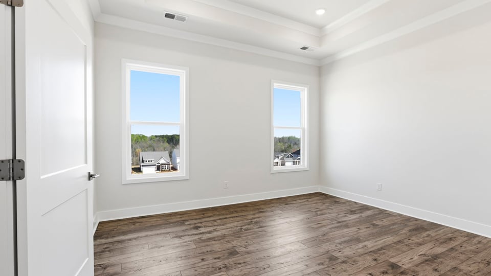 Primary bedroom on main level with trey ceiling, recessed lighting and two windows.