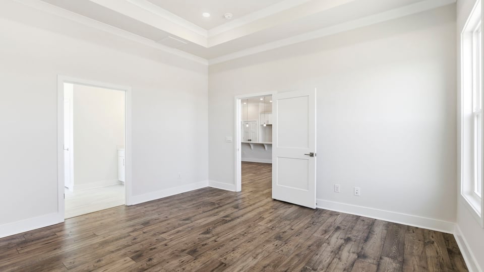 Primary bedroom on main level with trey ceiling, recessed lighting and two windows.