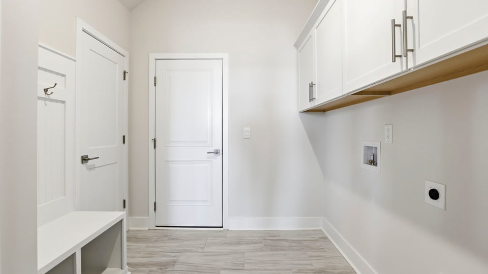 Walk-in laundry room with cabinets and drop zone.