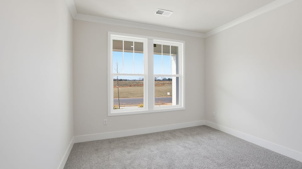 Bedroom at the front of the home with double window and carpet.