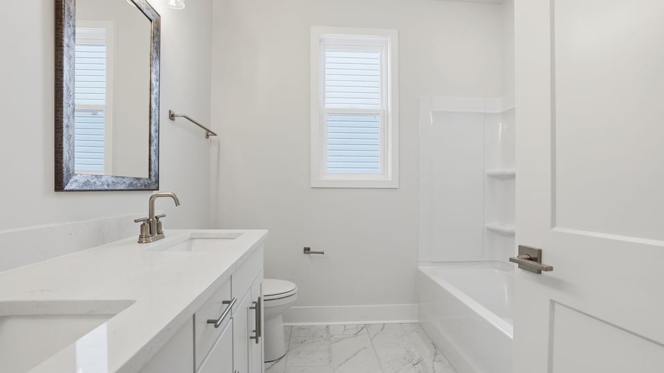Hall bathroom with dual sink vanity and combination shower / tub.