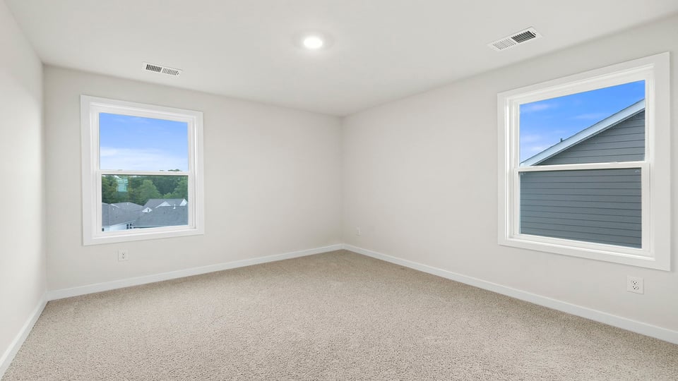 Primary bedroom with carpet and window.