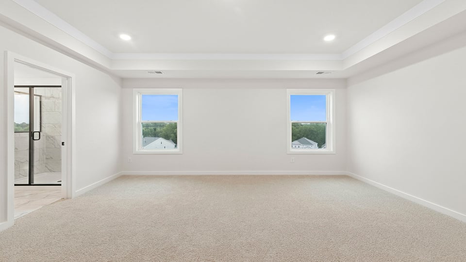 Primary bedroom with carpet and window.