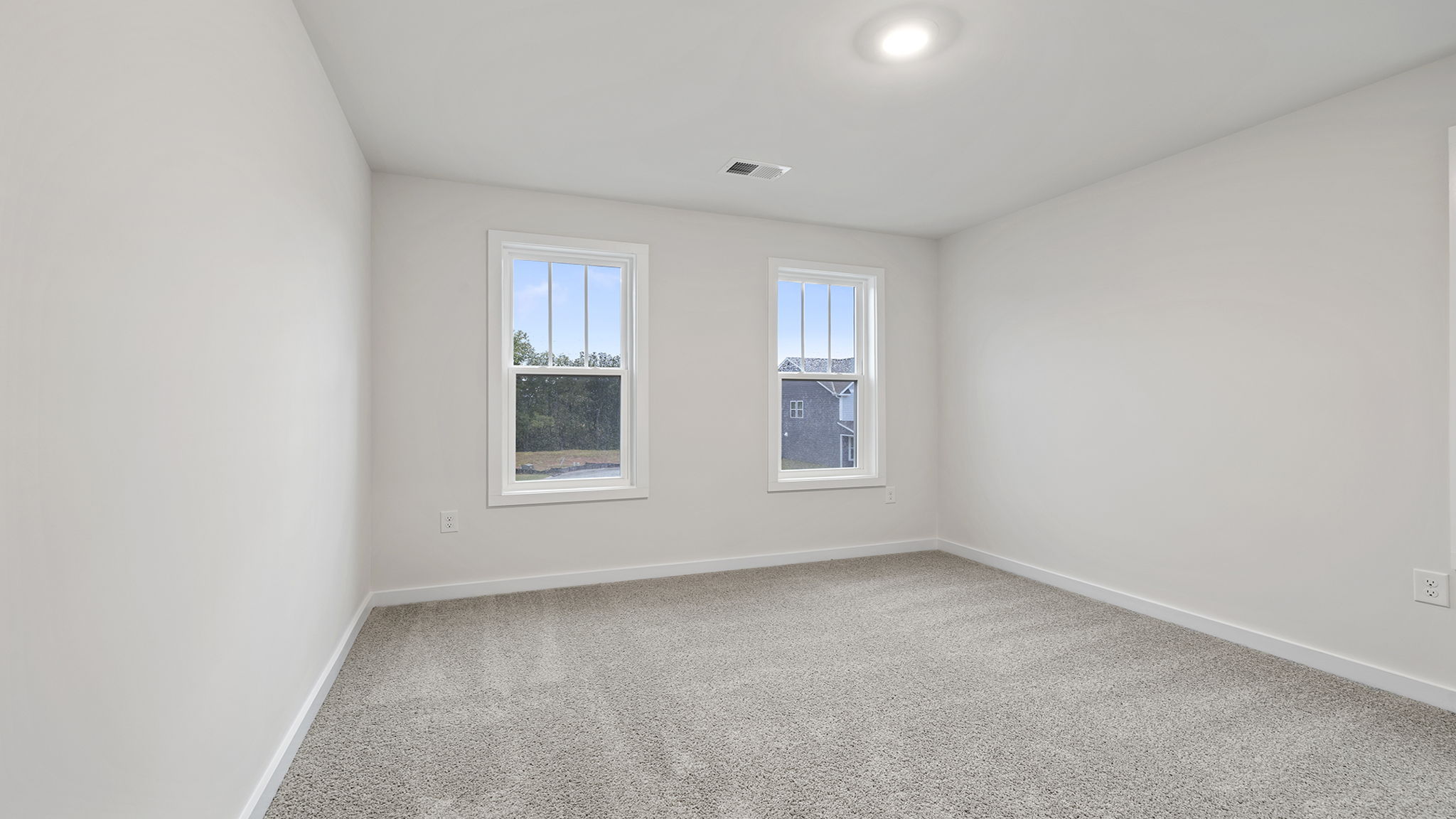Bedroom with carpet and two windows.