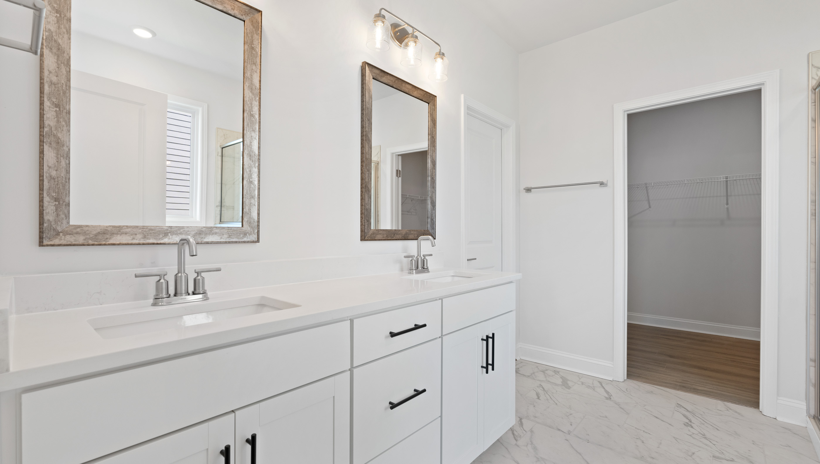 Primary bathroom with dual sink vanity and mirrors.