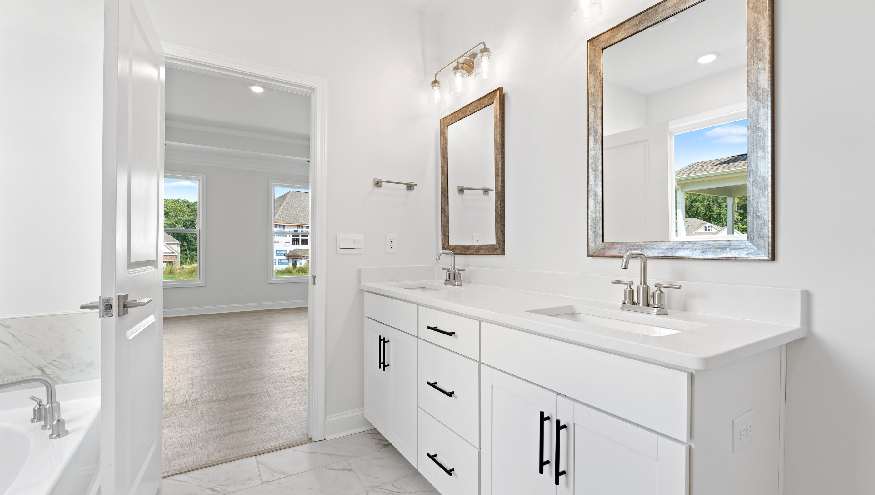 Primary bathroom with dual sink vanity and mirrors.