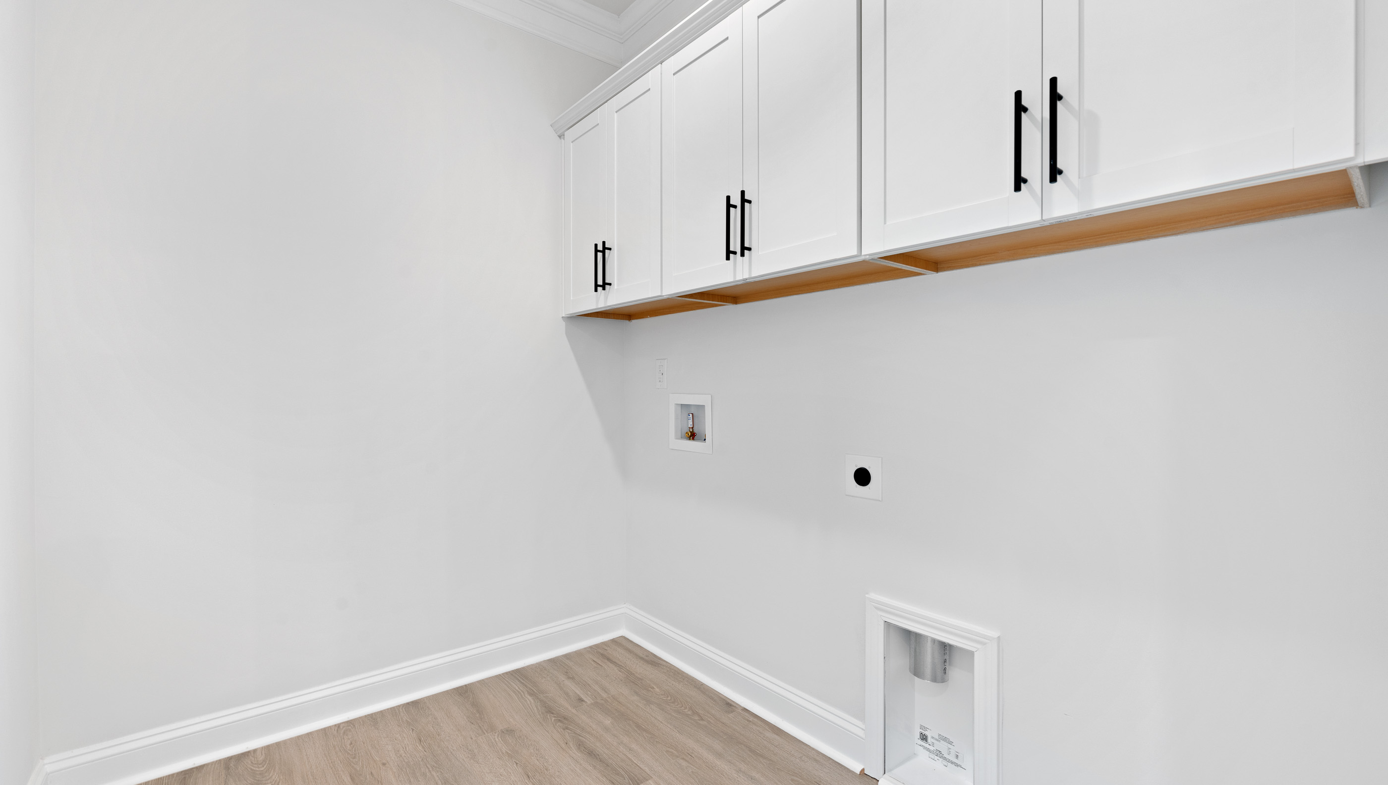 Walk-in laundry room with cabinets.
