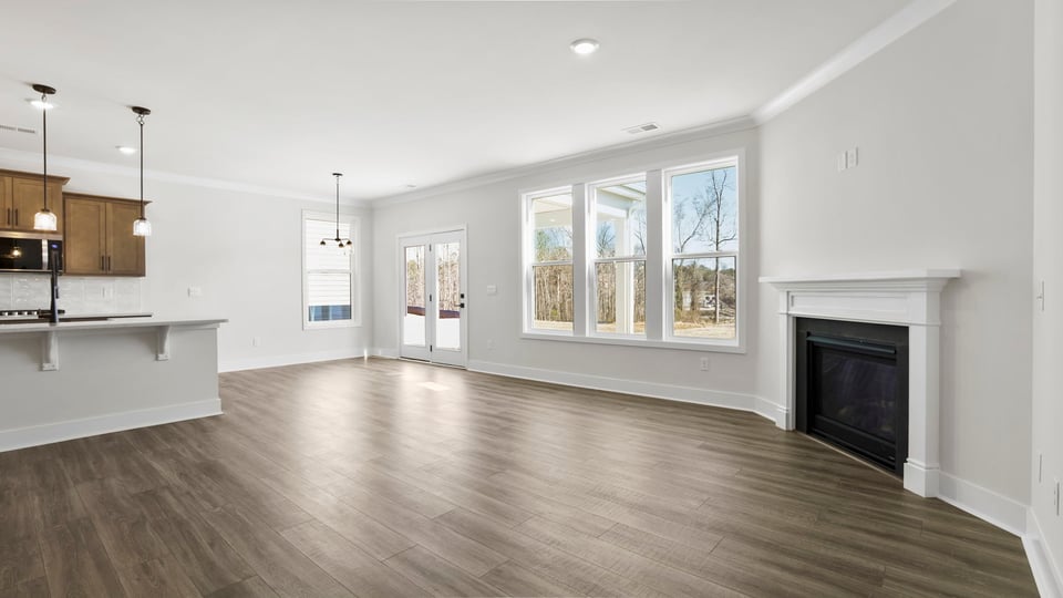 View of family room with gas log fireplace, wall of windows and open to the kitchen and breakfast room.