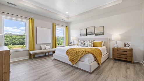 Primary bedroom with carpet and windows.