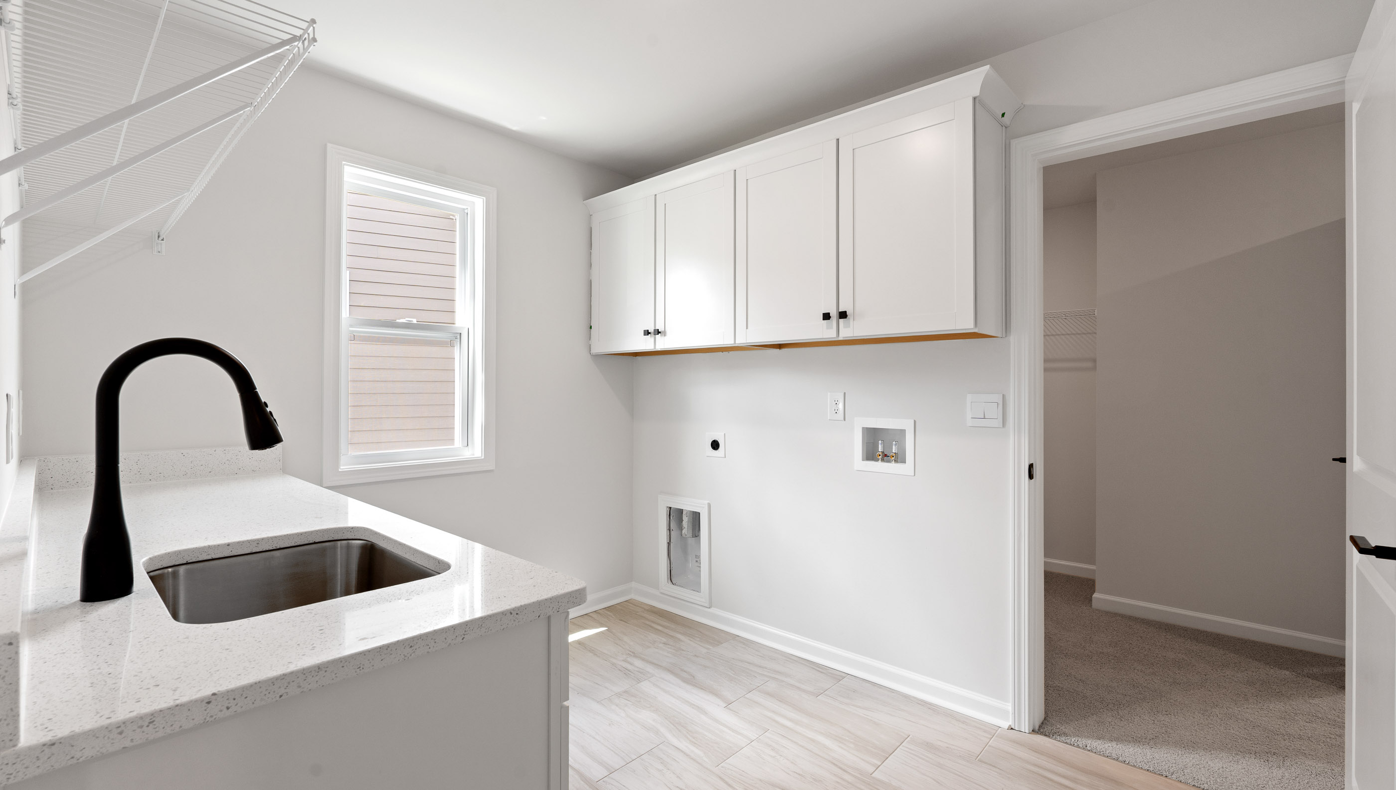 Laundry room with cabinets, sink and shelving.