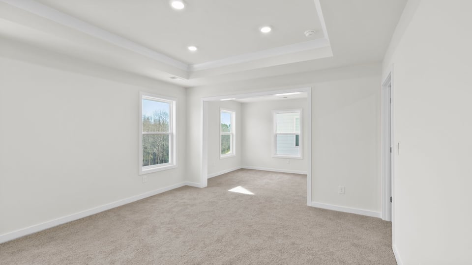 Primary bedroom with carpet and windows.