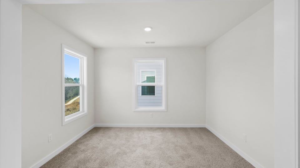 Primary bedroom with carpet and windows.