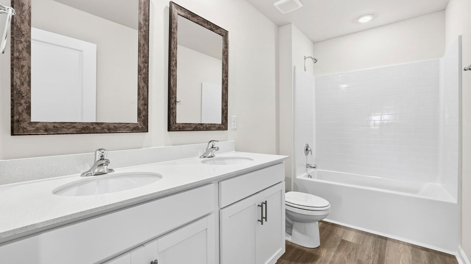Bathroom with double vanity sink. toilet, and tile shower