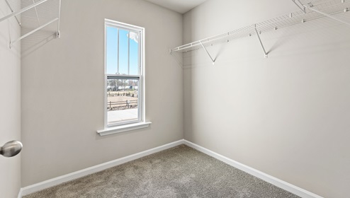 Walk in closet of master bedroom with window.