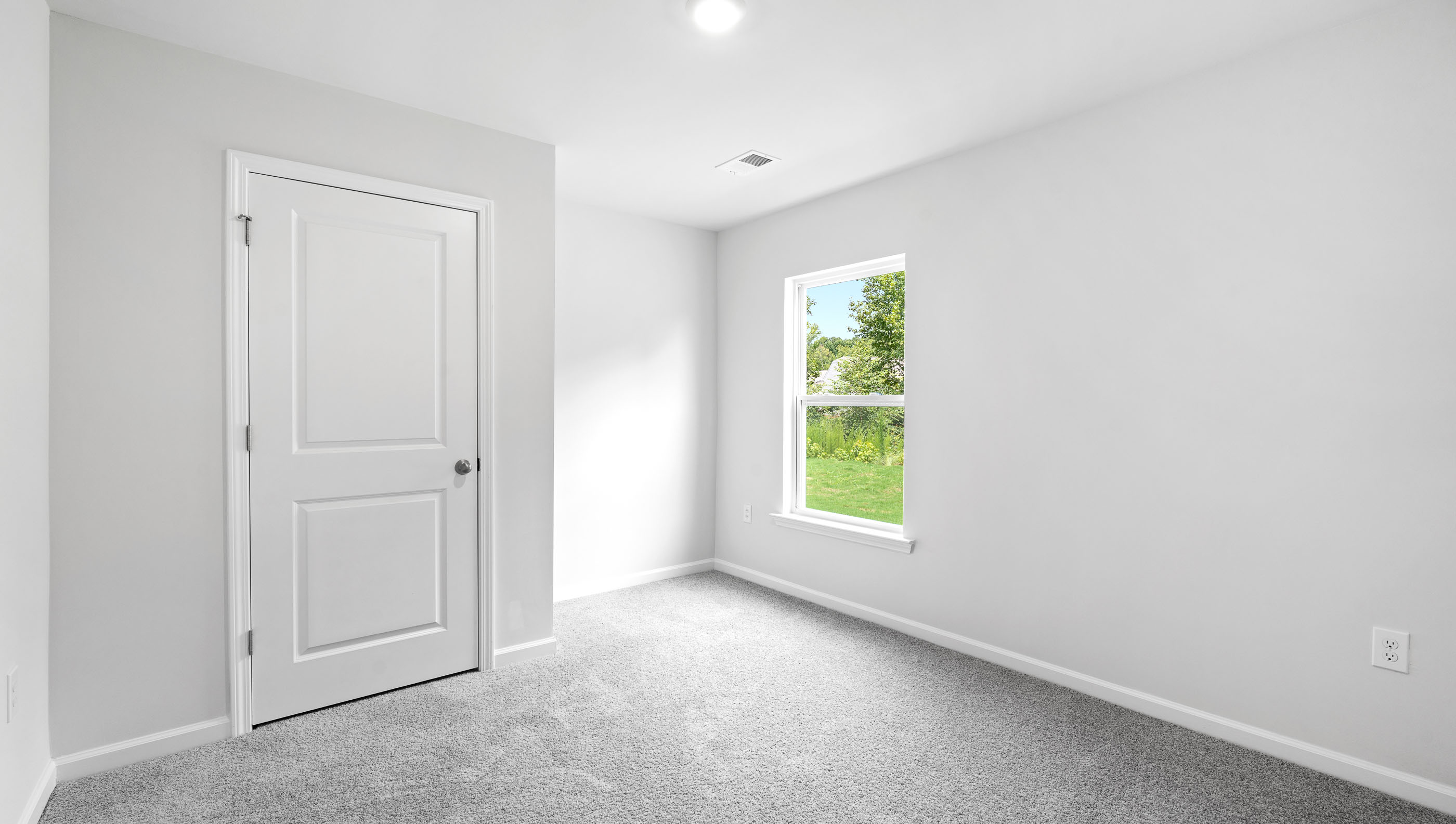 Bedroom with carpet and small window.