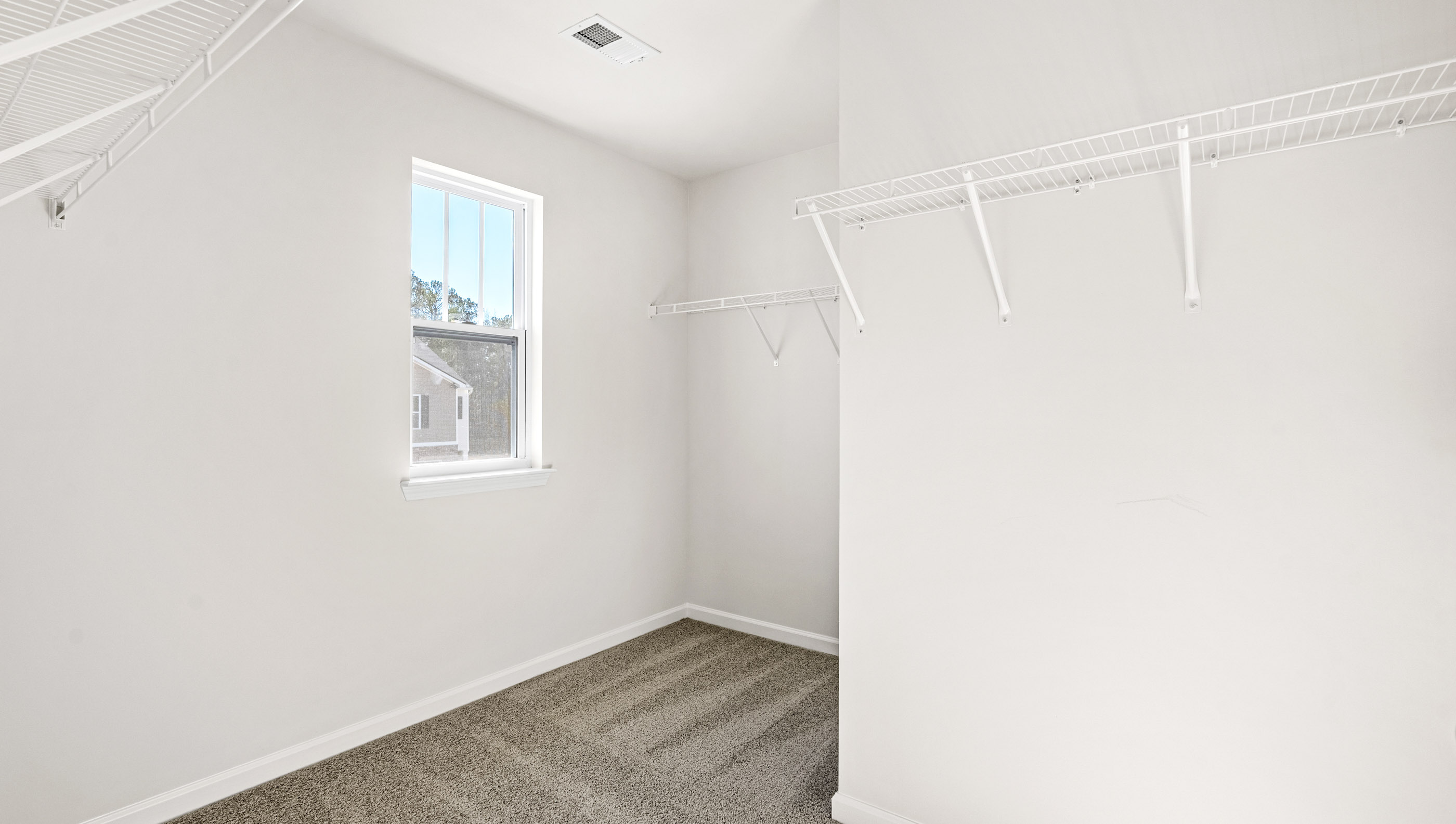 Walk in closet with window and hanging shelves.