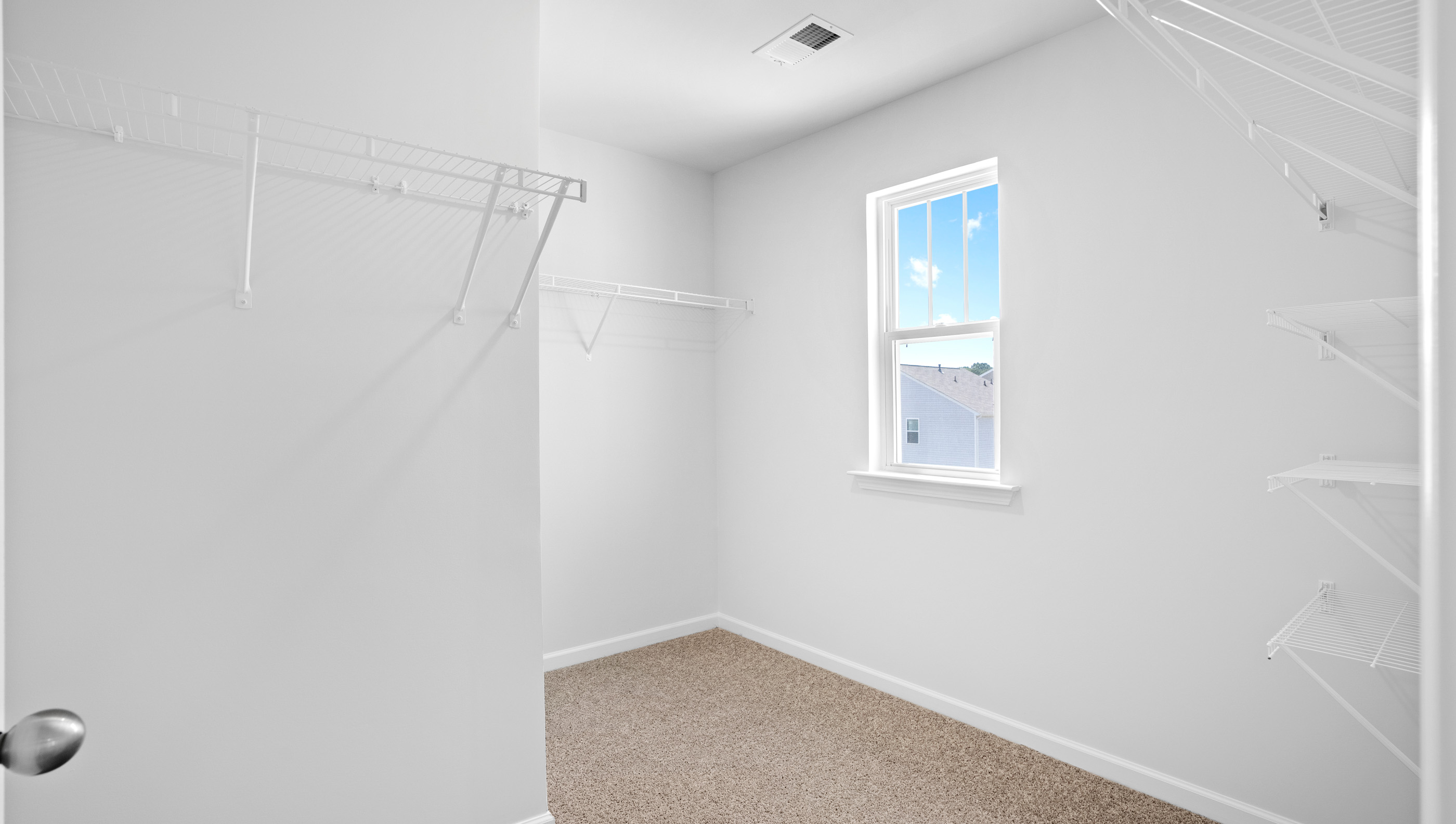 Walk in closet with shelves and window.
