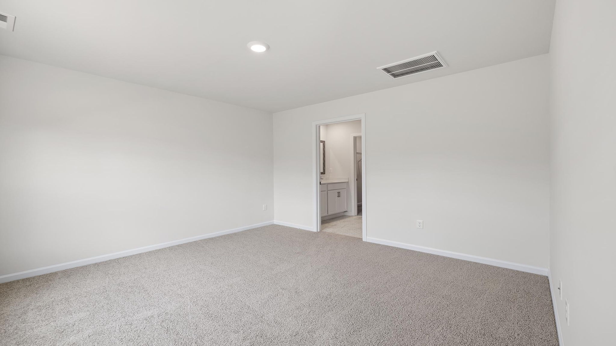 Primary bedroom with carpet and windows.