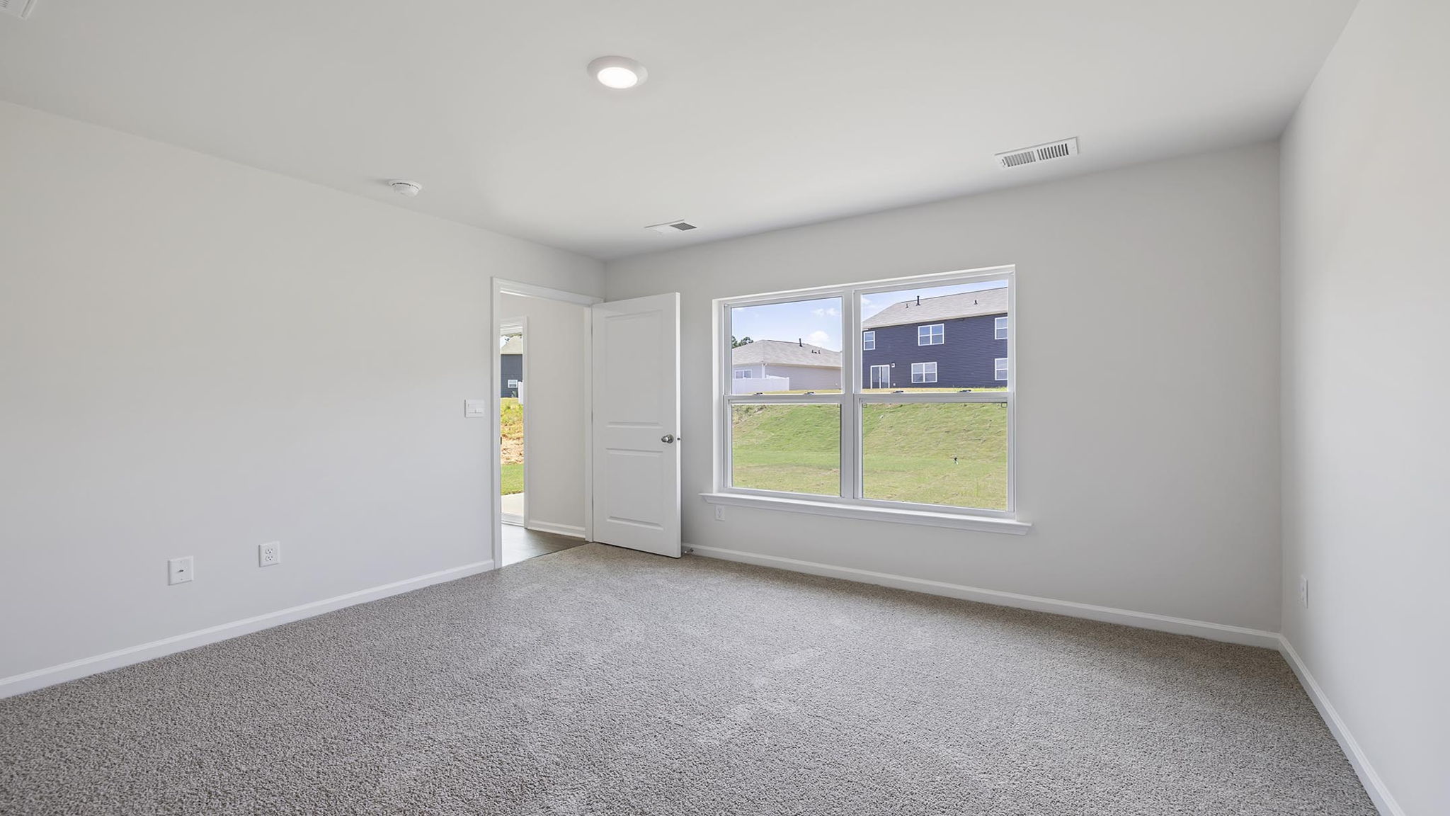 Primary bedroom with carpet and windows.